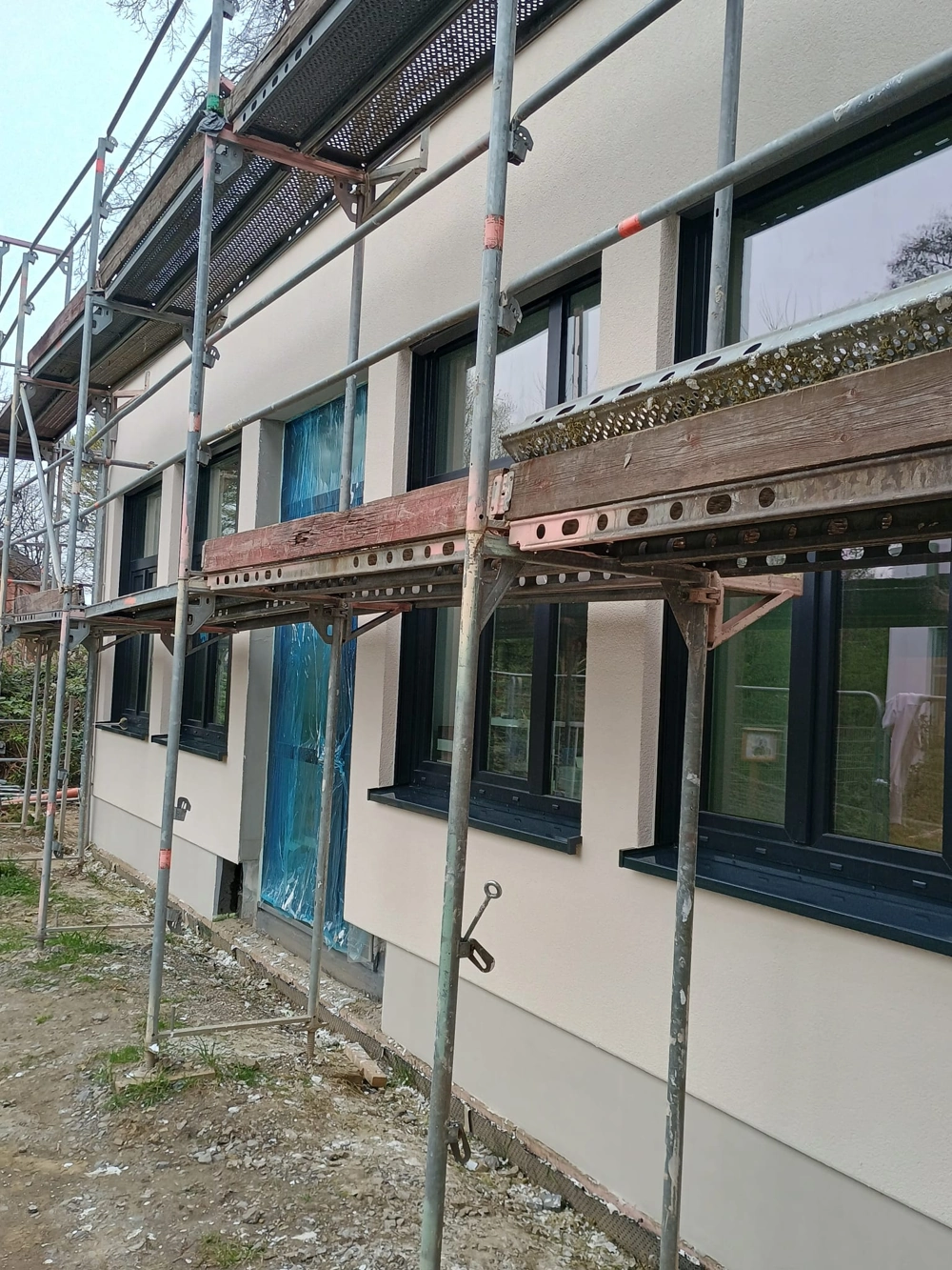 Gerüst vor frisch verputzter Außenfassade mit neuen Fenstern Außenputz