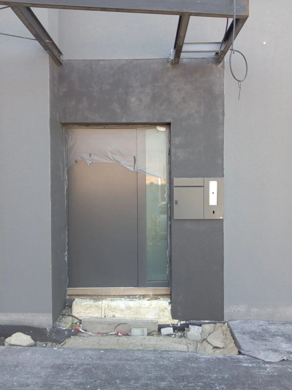 Graue Außenfassade mit Aluminium Haustüren und sichtbarem WDVS-Dämmmaterial am Sockel