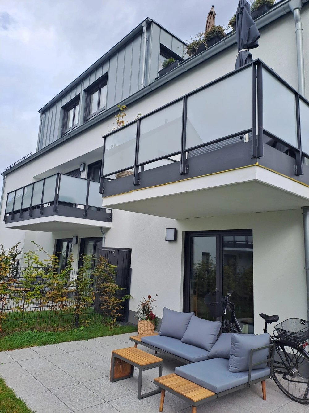 Fassadenbau: Moderne weiße Fassade mit bodentiefen Aluminiumfenstern und Glasbalkongeländern