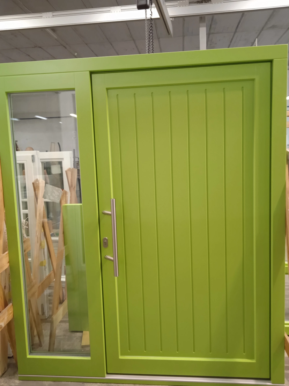Grüne Aluminium Haustüren mit vertikalen Profilen und seitlichem Glas-Seitenteil in Ausstellungsumgebung