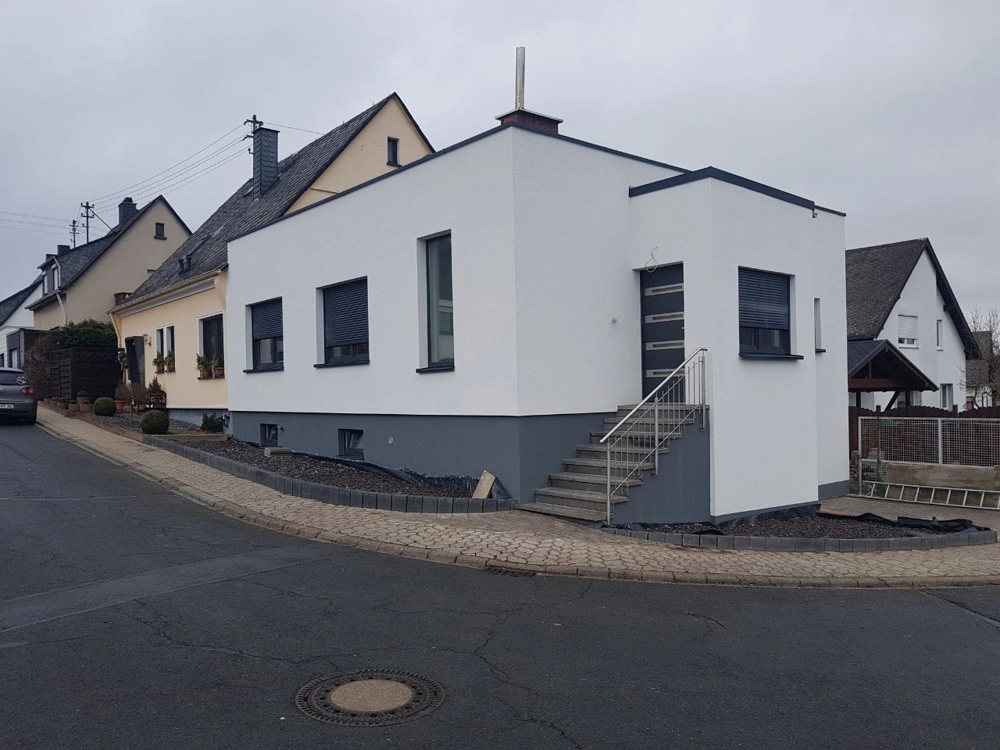 Fassadenanstrich an moderner weißer Gebäudeaußenfassade mit Kunststofffenstern und Rollläden