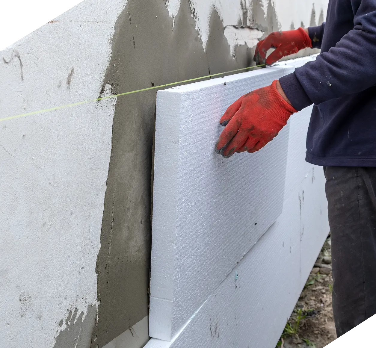 Monteur installiert weiße Dämmplatten im WDVS-System mit Klebemörtel an der Fassade