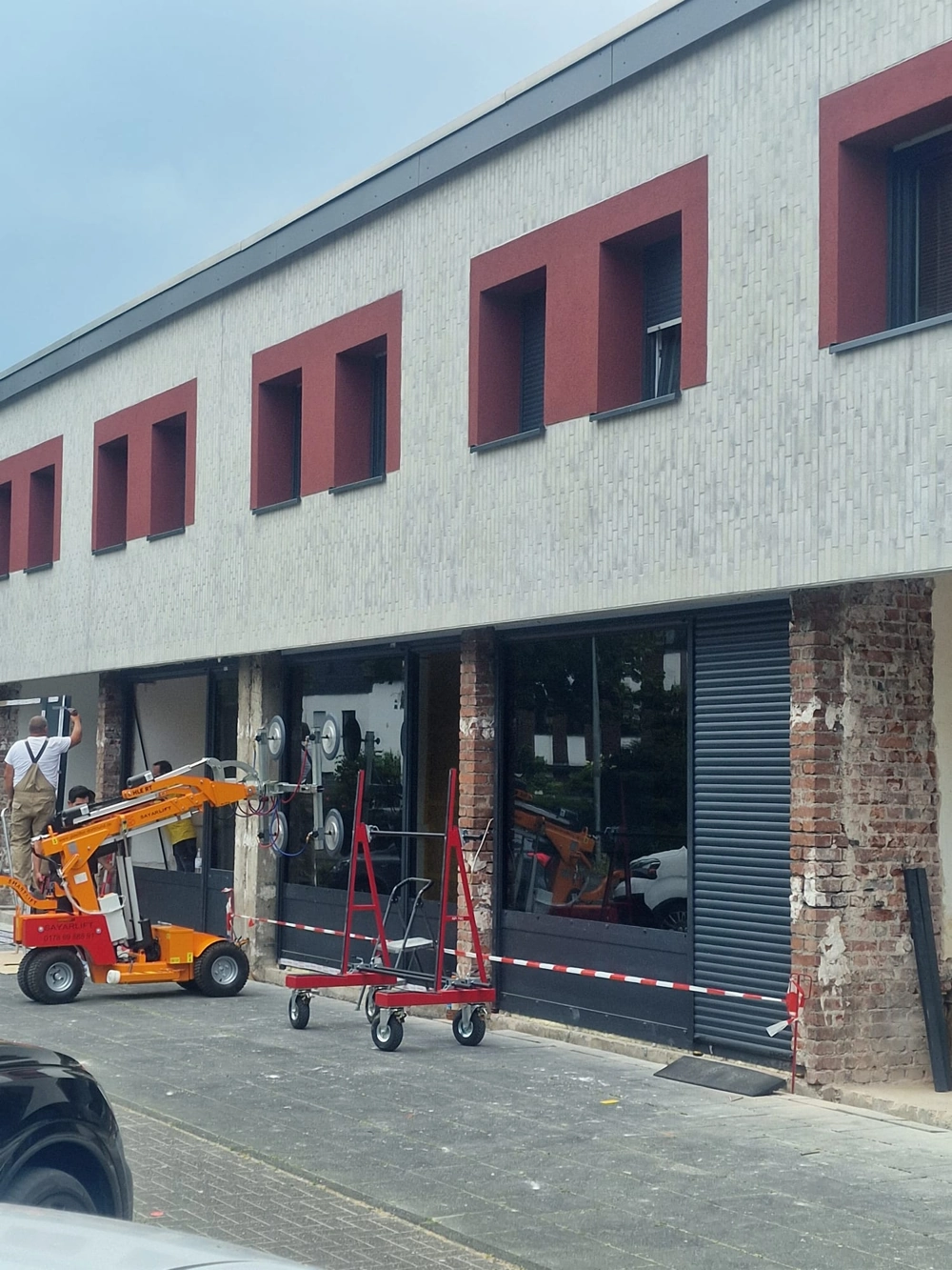 Fenstermontage mit Vakuumheber: Arbeiter setzt große Glasfenster in Gebäudefassade ein