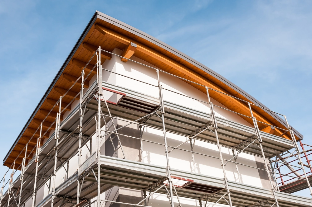 Gerüst an Hausgiebel während Fassadenbau mit sichtbaren Dämmplatten und Holzträgern