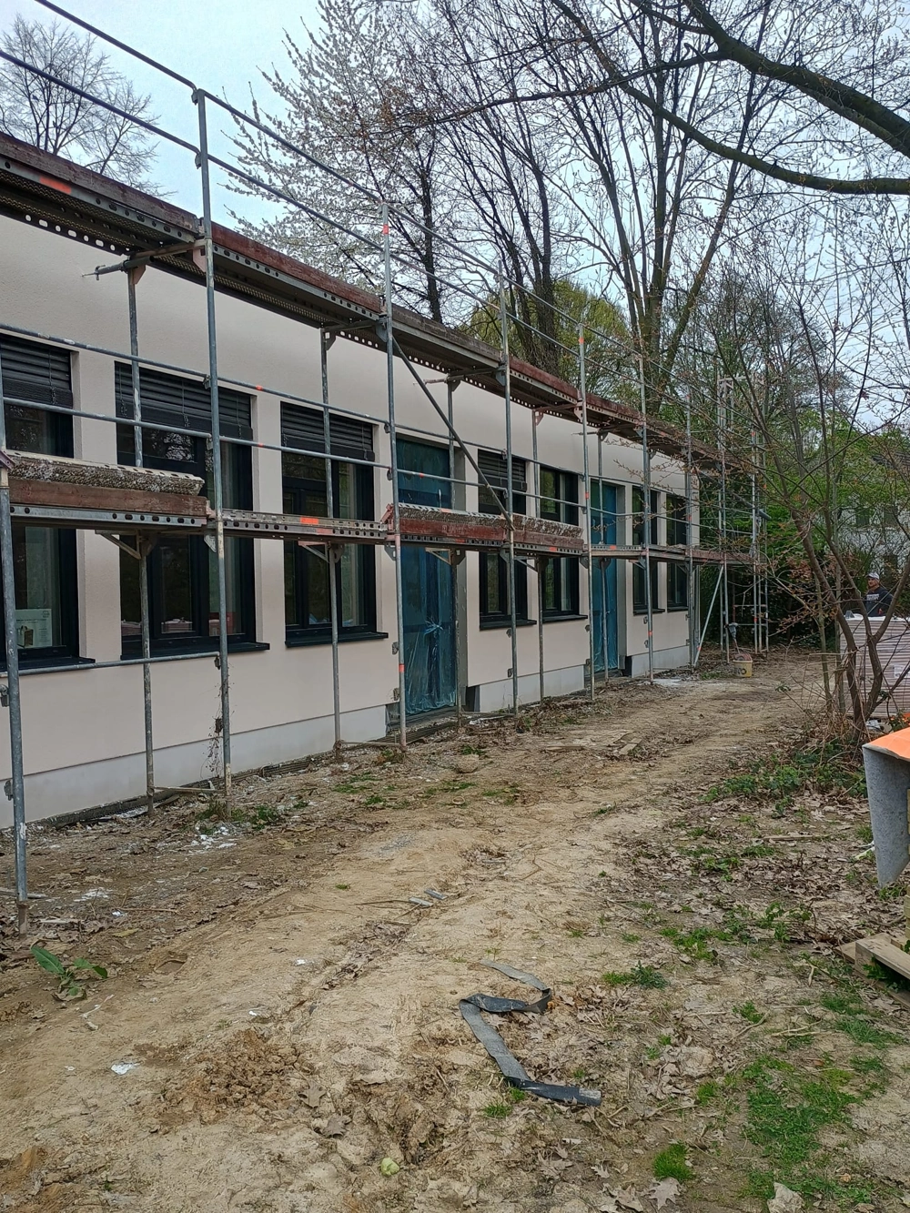 Gerüst vor einfarbiger Fassade mit frischem Außenputz an eingeschossigem Gewerbebau