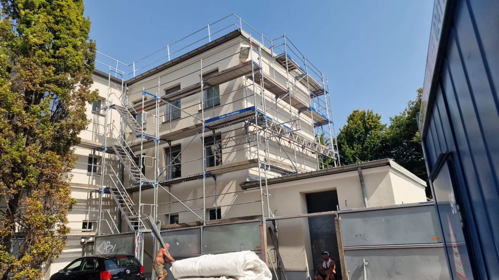 Mehrstöckiges Gebäude mit Gerüst und Arbeitern bei Fassadensanierung und Wärmedämmung