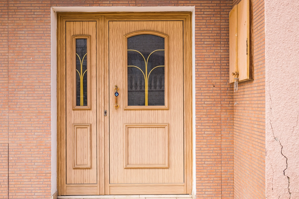 Holz Haustüren: Zweiflügelige Haustür aus hellem Holz mit dekorativen Glaseinsätzen in Klinkerfassade