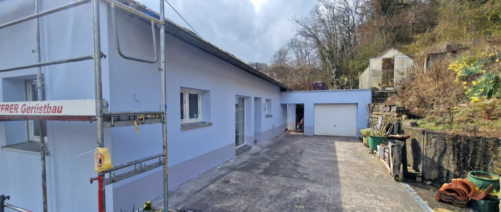 Fassadenanstrich an frisch gestrichener Hausfassade mit Garage und Baugerüst