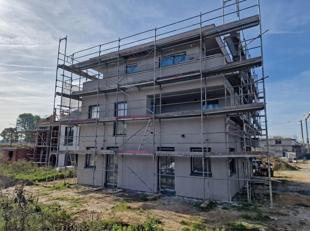 Mehrgeschossige Fassade mit Gerüst und frisch aufgetragenem Außenputz an Wohngebäude