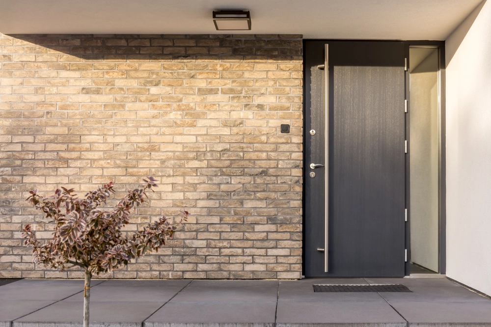 Anthrazitfarbene Aluminium Haustüren vor heller Klinkerfassade mit minimalistischem Eingangsbereich