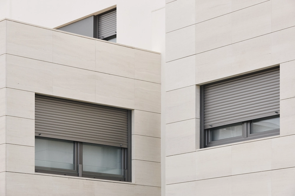 Helle, modern gestaltete Fassade mit grauem Aluminiumfenster und Rollladen, Fassadenbau