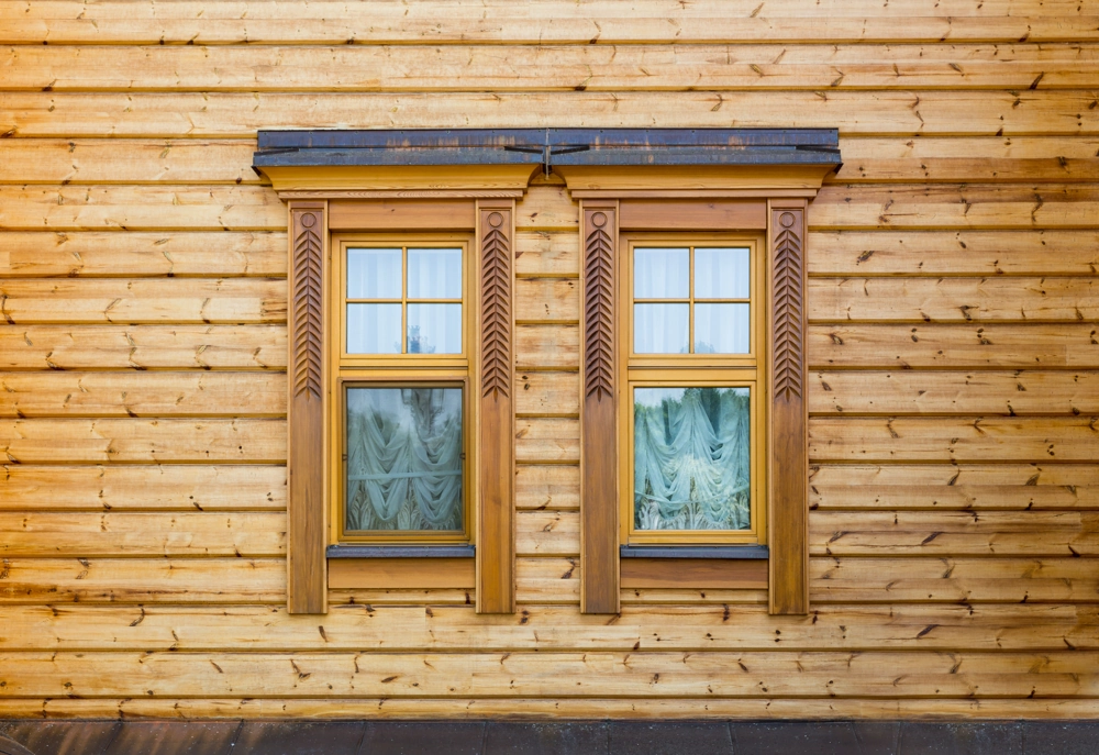 Holzfassade mit zwei Holzfenstern und dekorativem Rahmen, Fassadenbau