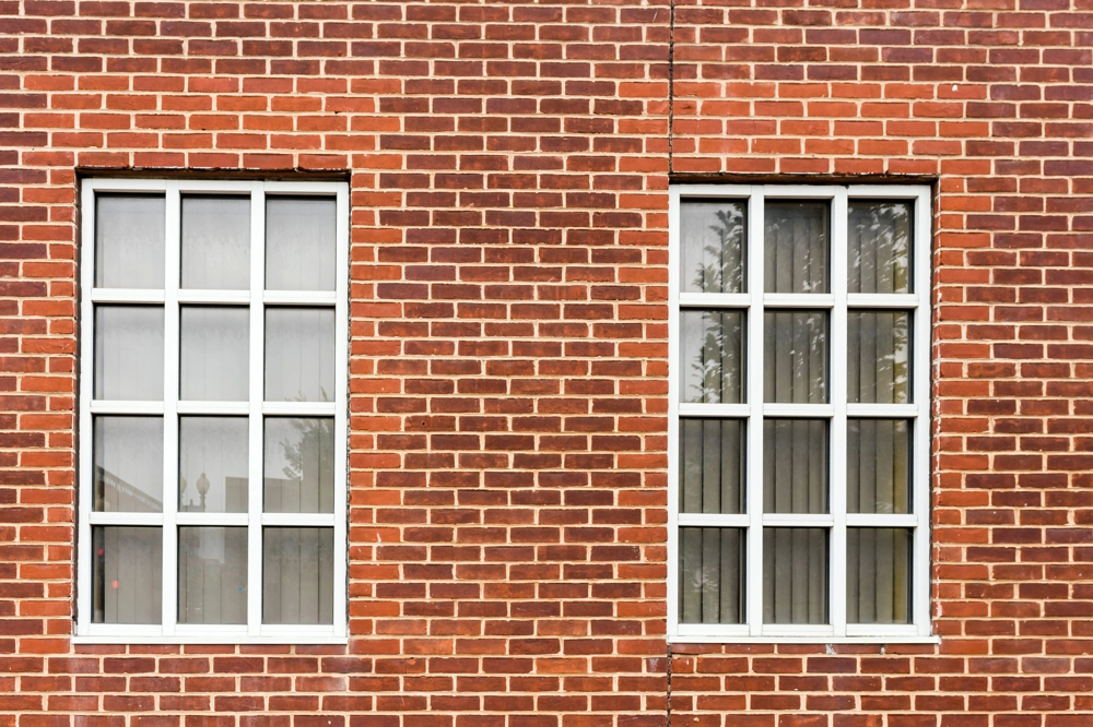 Zwei weiße Fenster mit Sprossen in roter Klinkerfassade